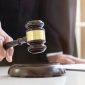 Close up of Male lawyer or judge hand's striking the gavel on sounding block, working with Law books, report the case on table in modern office, Law and justice concept.